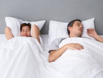 Angry Asian woman annoyed with husbands snoring