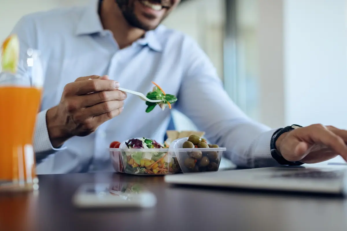 Man is eating healthy office snacks while working on laptop.