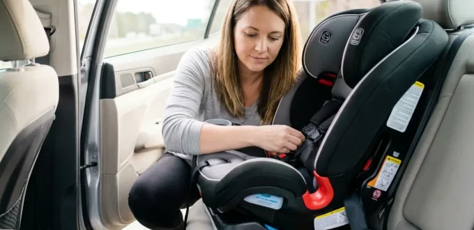 A woman carefully examines a rear-facing convertible car seat installed in a vehicle's back seat after a roadside incident.